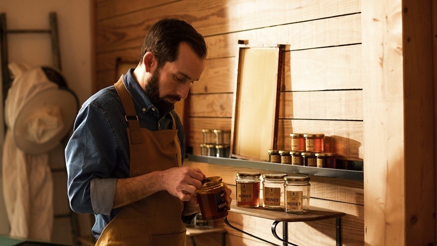 Apiculteur qui applique des étiquettes personnalisées pour pots de miel