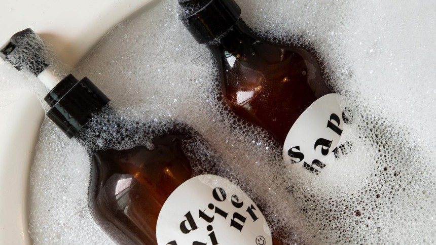 Etiquettes personnalisées waterproof collées sur des bouteilles de shampoing et conditionner plongées dans de l'eau savonneuse
