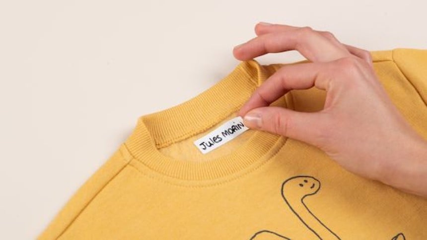 Main qui colle une étiquette vêtement autocollante sur un t-shirt jaune