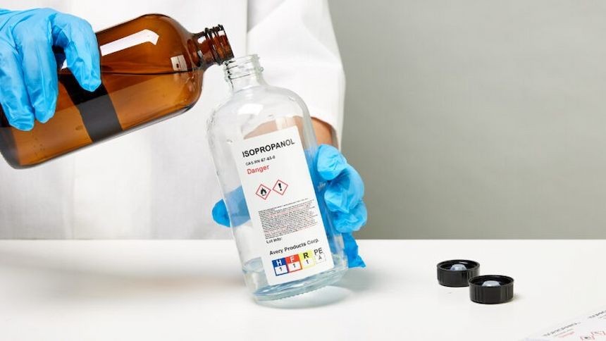 Personne en train de verser un produit chimique dans un flacon identifié avec une étiquette sgh