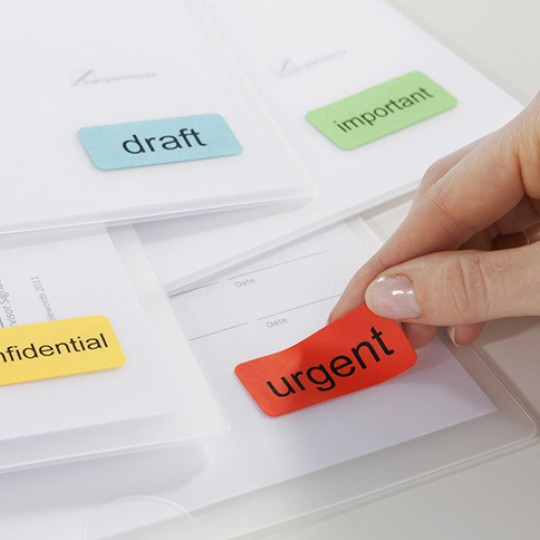 main en train de décoller une étiquette rouge décollable d'un document