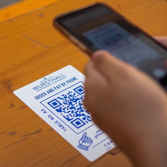 Personne en train de scanner un QR code imprimé sur un sticker collé sur une table