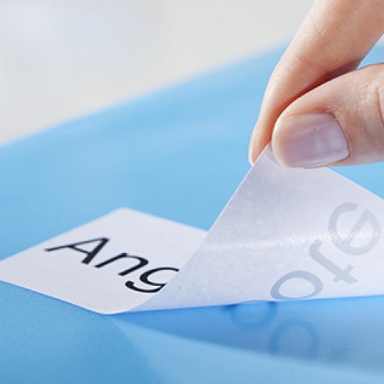Main qui décolle une étiquette en papier décollable