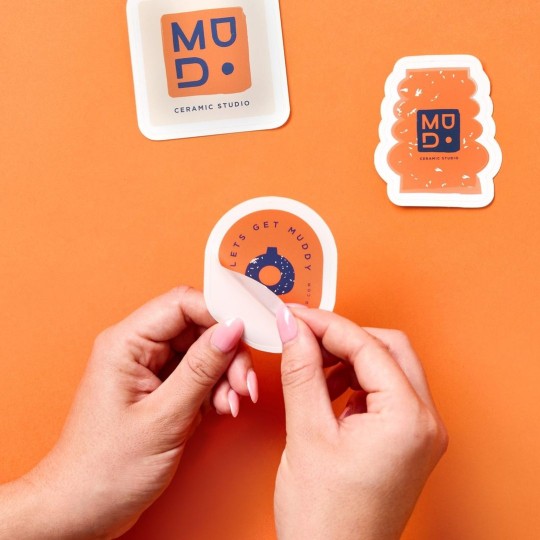 Mains qui décollent un sticker personnalisé découpé à la forme du design