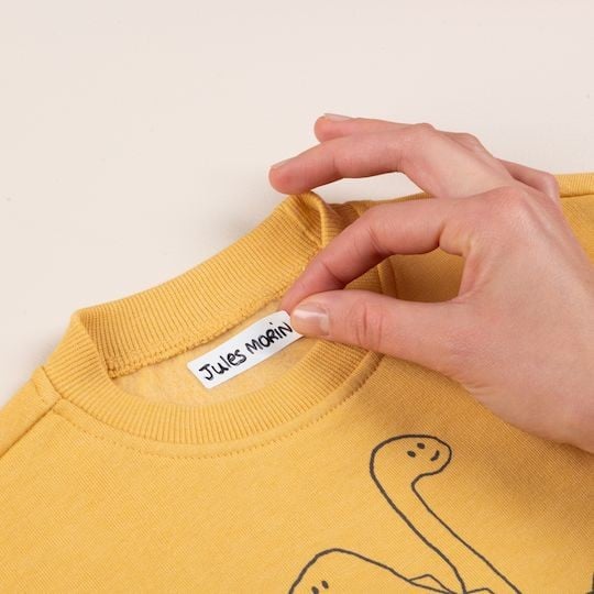 Main collant une étiquette autocollantes pour vêtements sur un t-shirt jaune