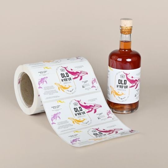 Etiquettes personnalisées pour spiritueux présentées en rouleau et sur une bouteille