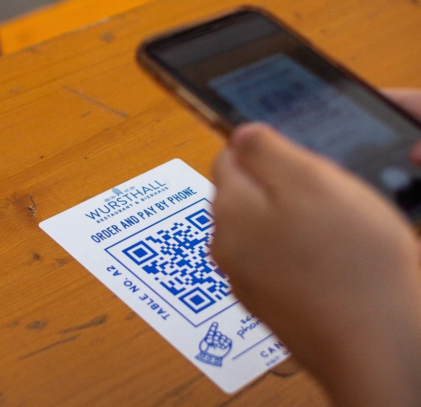 Personne en train de scanner un QR code imprimé sur un sticker collé sur une table