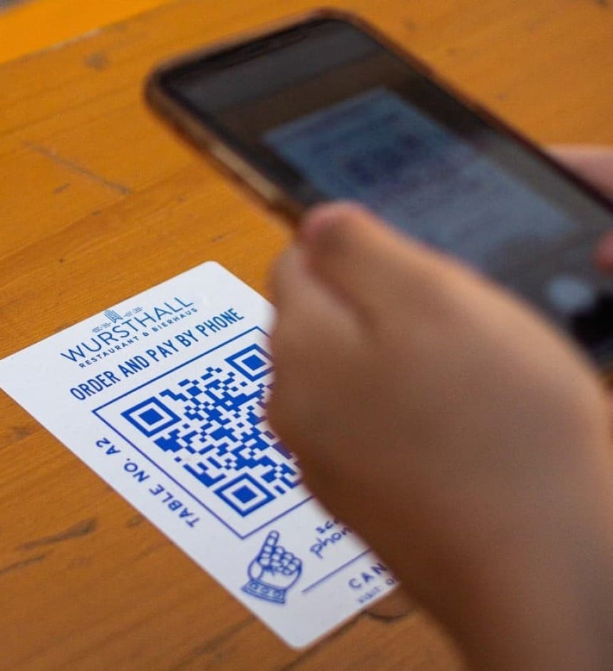 Personne en train de scanner un QR code imprimé sur un sticker collé sur une table