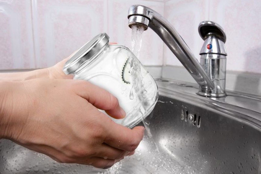 Désintégration d'une étiquette soluble collée sur un bocal au contact de l'eau sous le robinet