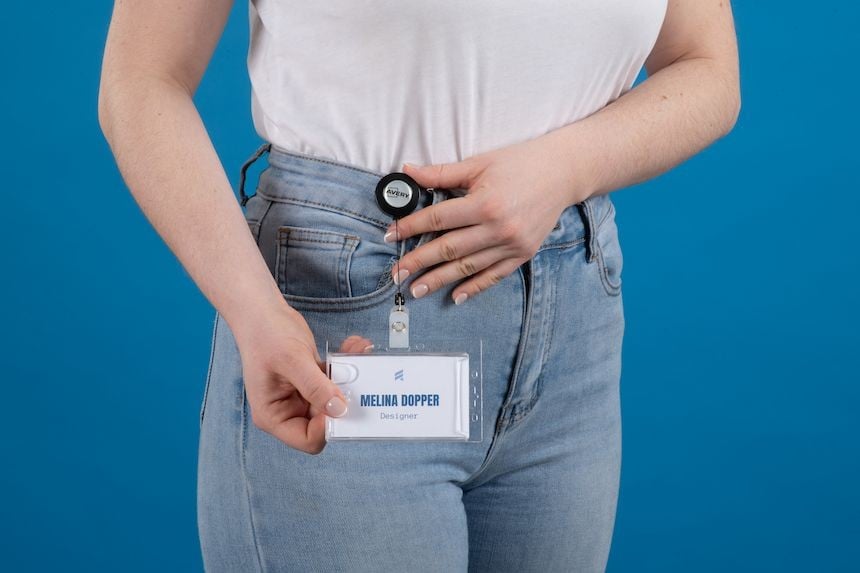Personne montrant un porte-badge rétractable avec enrouleur à clip attaché à la ceinture