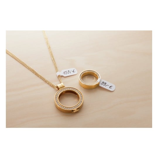 Une image montrant un collier doré avec un pendentif circulaire et une bague assortie. Les deux accessoires sont étiquetés avec des prix en euros.