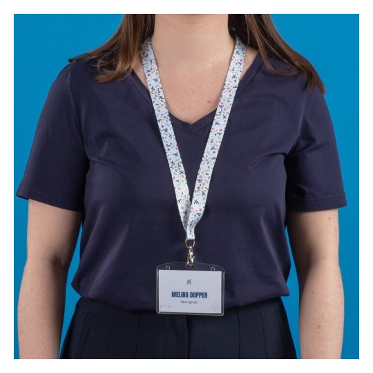L'image montre une personne portant un t-shirt bleu marine avec un badge d'identification suspendu à un lanyard floral.