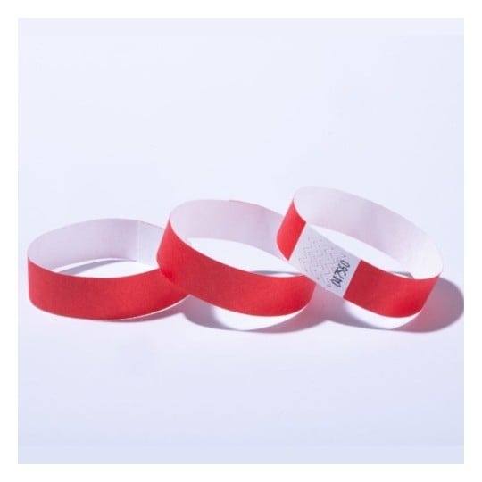 L'image montre trois bracelets en papier rouge, chacun ayant une partie blanche à l'intérieur. Ces bracelets sont souvent utilisés lors des événements, des festivals ou des concerts pour identifier les participants.