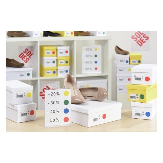 L'image montre des chaussures exposées avec des étiquettes de promotions indiquant des remises allant de 20% à 50%. Les boîtes à chaussures sont bien alignées, et il y a une signalisation pour les soldes.