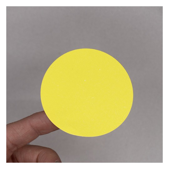L'image montre un cercle jaune tenue par une main, sur un fond gris.