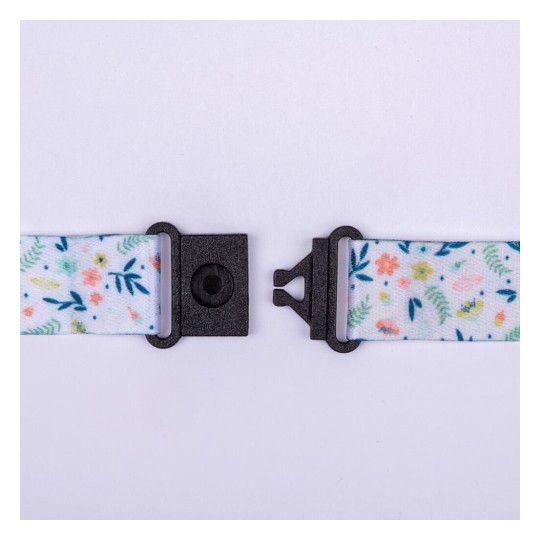 L'image montre une sangle colorée avec des motifs floraux tenue par des attaches noires.