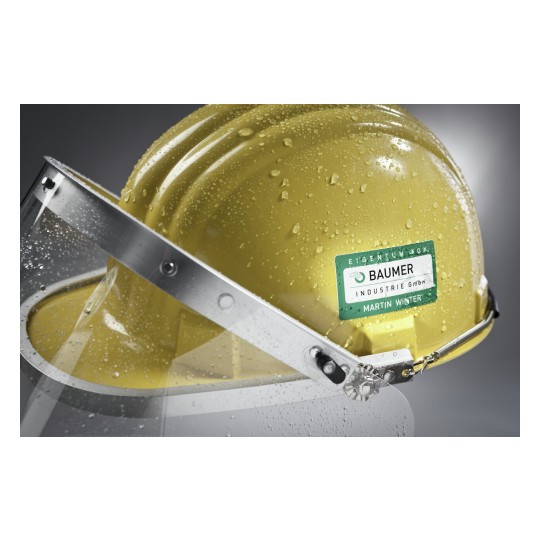 Il s'agit d'un casque de sécurité jaune avec une visière, portant un autocollant d'une entreprise. Le casque est couvert de gouttes d'eau.