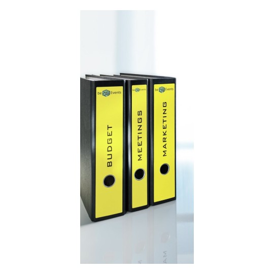 L'image montre trois classeurs étiquetés 'BUDGET', 'MEETINGS' et 'MARKETING', disposés sur une surface réfléchissante. Ils sont de couleur noire avec des étiquettes jaunes.