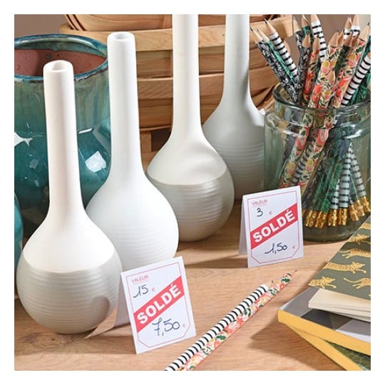 L'image montre des vases en céramique avec des étiquettes de réduction, des pailles décoratives et des livres ou carnets en arrière-plan.