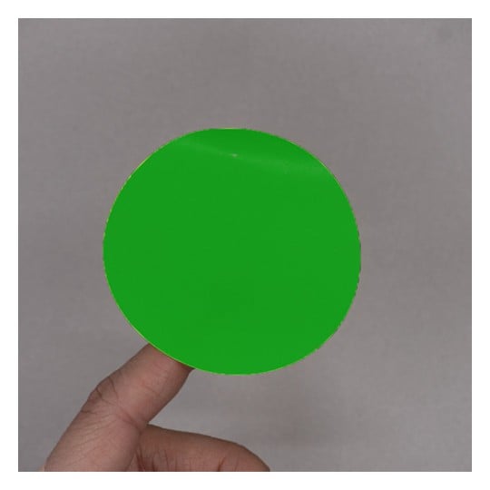 L'image montre un cercle vert brillant tenu par une main contre un fond uniforme.