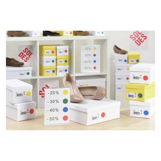 L'image montre des chaussures exposées sur une table avec des boîtes de rangement, ainsi que des panneaux indiquant des réductions de prix. Les boîtes sont de différentes couleurs.