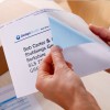 main décollant une étiquette opaque, faisant apparaitre la fine couche bleue qui empêche de voir à travers