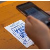 Personne en train de scanner un QR code imprimé sur un sticker collé sur une table