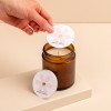 Main positionnant une protection pour bougie personnalisée sur une bougie