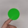 Une main tenant un disque de couleur verte.