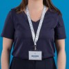 L'image montre une personne portant un t-shirt bleu marine avec un badge d'identification suspendu à un lanyard floral.