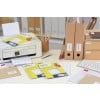Cette image montre un bureau organisé avec une imprimante, des étiquettes Avery, des dossiers, des enveloppes et un clavier.