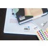 Une image montrant des livres empilés avec des étiquettes et des autocollants colorés sur une table.