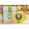 L'image montre une boîte blanche avec un ruban vert portant le logo de 'Flowette Soap Company' et un savon en glycérine de couleur orange à côté.
