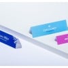 L'image montre des cartes de visite en plastique avec des noms et titres professionnels. Les cartes sont de différentes couleurs: bleu, violet, et rose.