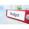L'image montre un classeur rouge avec l'inscription "Budget" sur une étiquette blanche.