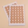 Deux feuilles autocollantes contenant des étiquettes circulaires avec le mot 'Merci' imprimé en blanc sur un fond brun.
