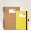 L'image montre deux carnets de notes. Le carnet de gauche est en liège et de format A5, tandis que celui de droite est jaune avec une couverture lisse et un élastique de maintien.