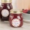 Des pots de confiture de fruits rouges avec des étiquettes sur un fond flou, entourés de baies.