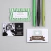 Cette image montre plusieurs cartes de visite disposées sur une surface grise avec des stylos colorés à proximité. Les cartes incluent une pour une bijouterie nommée 'TRESOR', une pour le photographe Paul Delauney, et une autre pour 'Chez Léa', un salon de thé.