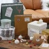 L'image montre des cadeaux et des décorations de Noël, y compris des boîtes emballées, des étiquettes de cadeaux, et des ornements sur une table en bois.